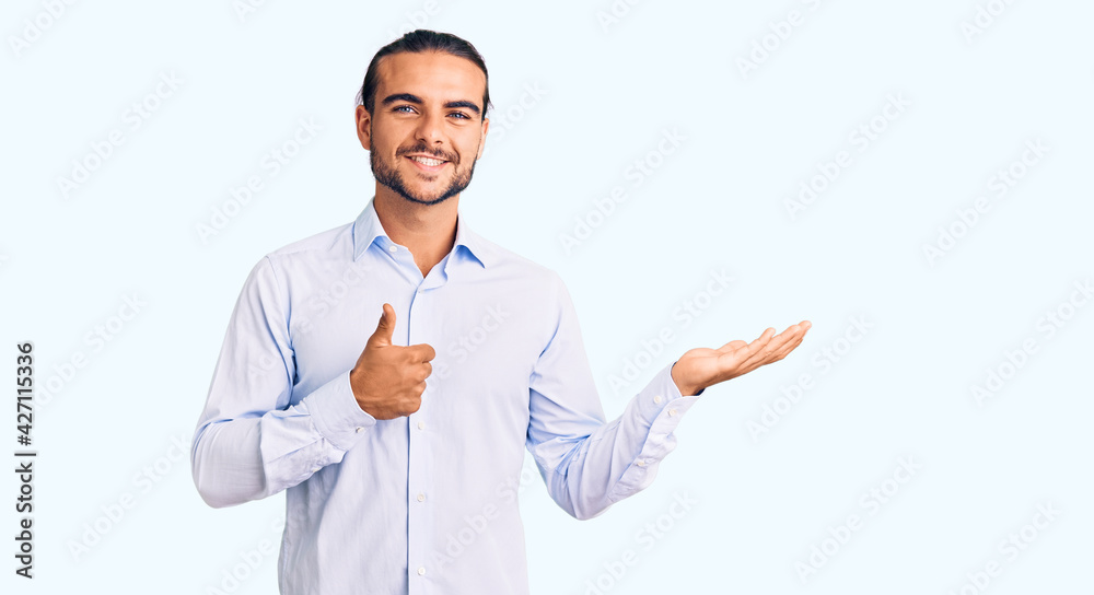 Young handsome man wearing business clothes showing palm hand and doing ok gesture with thumbs up, smiling happy and cheerful Young handsome man wearing business clothes showing palm hand and doing ok gesture with thumbs up, smiling happy and cheerful