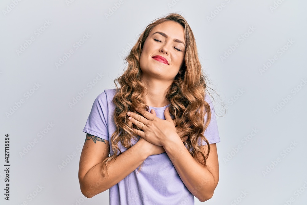 Young blonde girl wearing casual clothes smiling with hands on chest, eyes closed with grateful gesture on face. health concept. Young blonde girl wearing casual clothes smiling with hands on chest, eyes closed with grateful gesture on face. health concept.