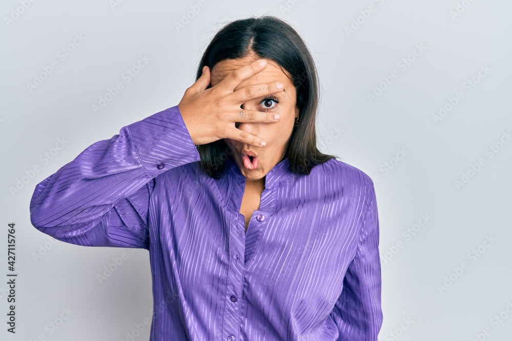 Young brunette woman wearing casual clothes peeking in shock covering face and eyes with hand, looking through fingers with embarrassed expression. Young brunette woman wearing casual clothes peeking in shock covering face and eyes with hand, looking through fingers with embarrassed expression.