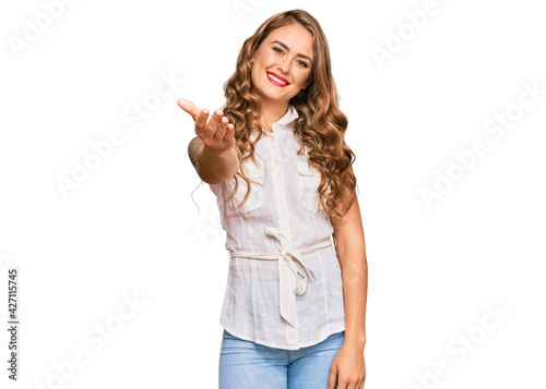 Young blonde girl wearing casual clothes smiling friendly offering handshake as greeting and welcoming. successful business.