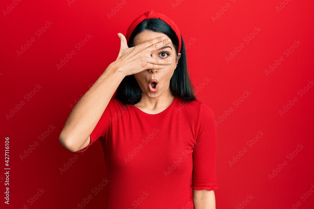 Young hispanic woman wearing casual clothes peeking in shock covering face and eyes with hand, looking through fingers afraid Young hispanic woman wearing casual clothes peeking in shock covering face and eyes with hand, looking through fingers afraid