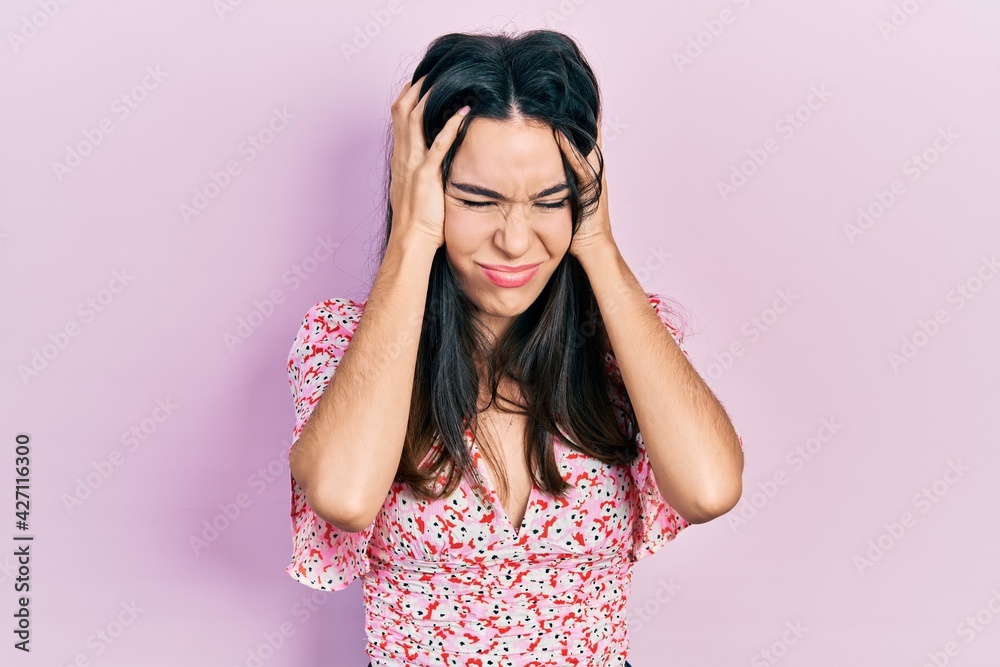 Young brunette woman wearing summer dress suffering from headache desperate and stressed because pain and migraine. hands on head. Young brunette woman wearing summer dress suffering from headache desperate and stressed because pain and migraine. hands on head.