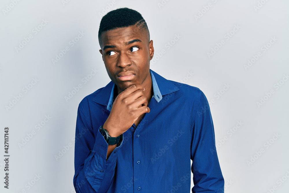 Young african american man wearing casual clothes thinking concentrated about doubt with finger on chin and looking up wondering