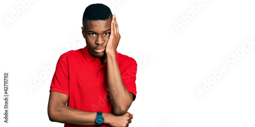 Tableau sur toile Young african american man wearing casual red t shirt thinking looking tired and bored with depression problems with crossed arms