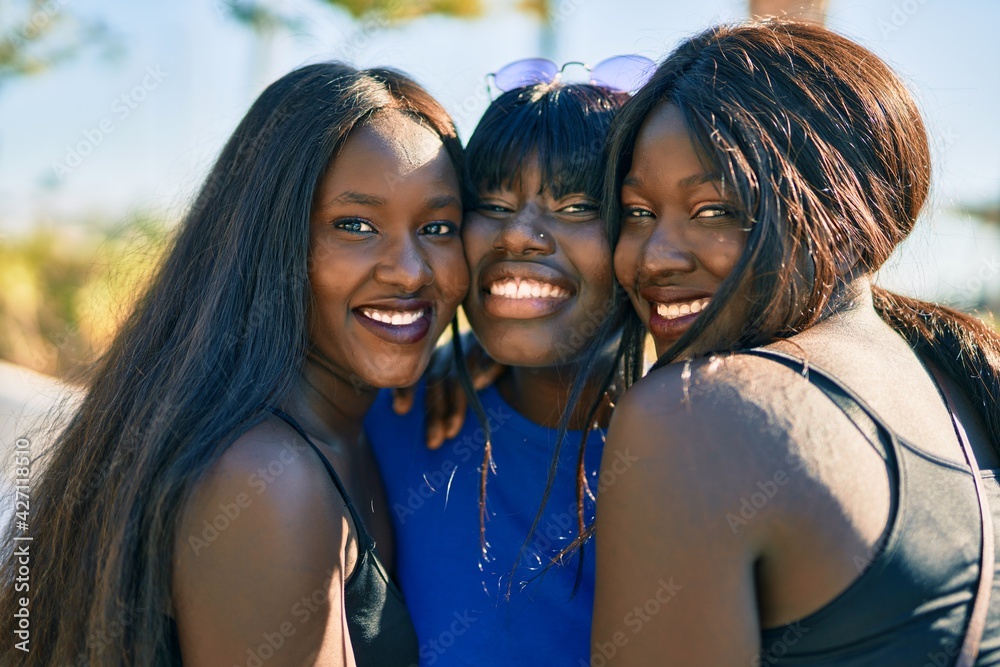 Three african american friends smiling happy hugging at the city.