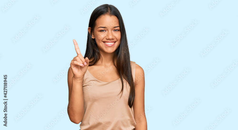 Beautiful hispanic woman wearing casual clothes showing and pointing up with finger number one while smiling confident and happy. Beautiful hispanic woman wearing casual clothes showing and pointing up with finger number one while smiling confident and happy.