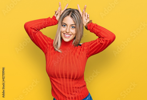 Beautiful blonde woman wearing casual clothes posing funny and crazy with fingers on head as bunny ears, smiling cheerful