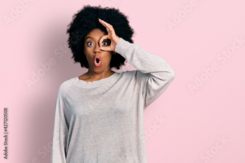 Young african american woman wearing casual clothes doing ok gesture shocked with surprised face, eye looking through fingers. unbelieving expression. © Krakenimages.com