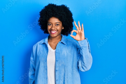Young african american woman wearing casual clothes smiling positive doing ok sign with hand and fingers. successful expression.