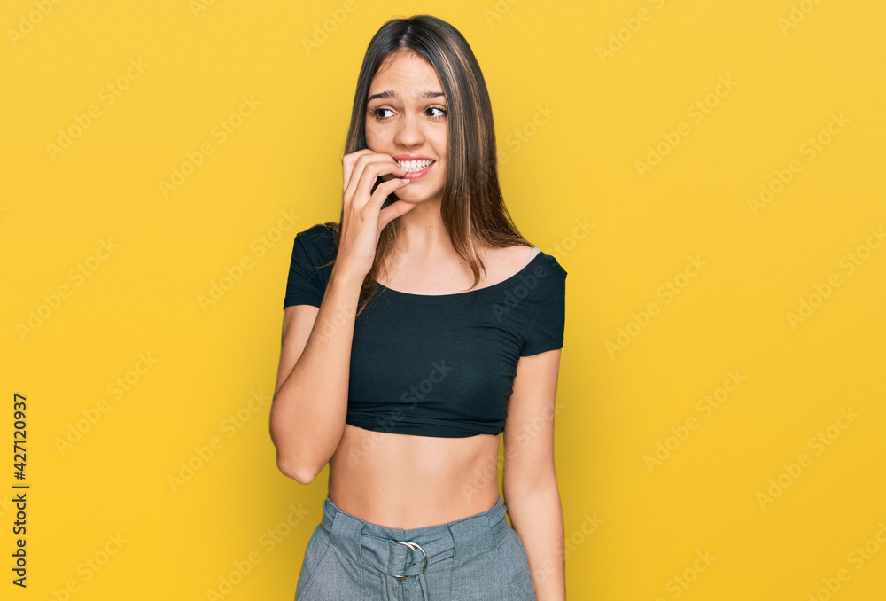 Young brunette woman wearing casual clothes looking stressed and nervous with hands on mouth biting nails. anxiety problem. Young brunette woman wearing casual clothes looking stressed and nervous with hands on mouth biting nails. anxiety problem.