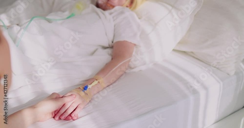 mother holding a hand of acutely sick kid with intravenous fluid therapy and oxygen mask for lung ventilation photo