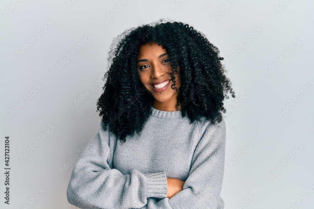 African american woman with afro hair wearing casual winter sweater happy face smiling with crossed arms looking at the camera. positive person.