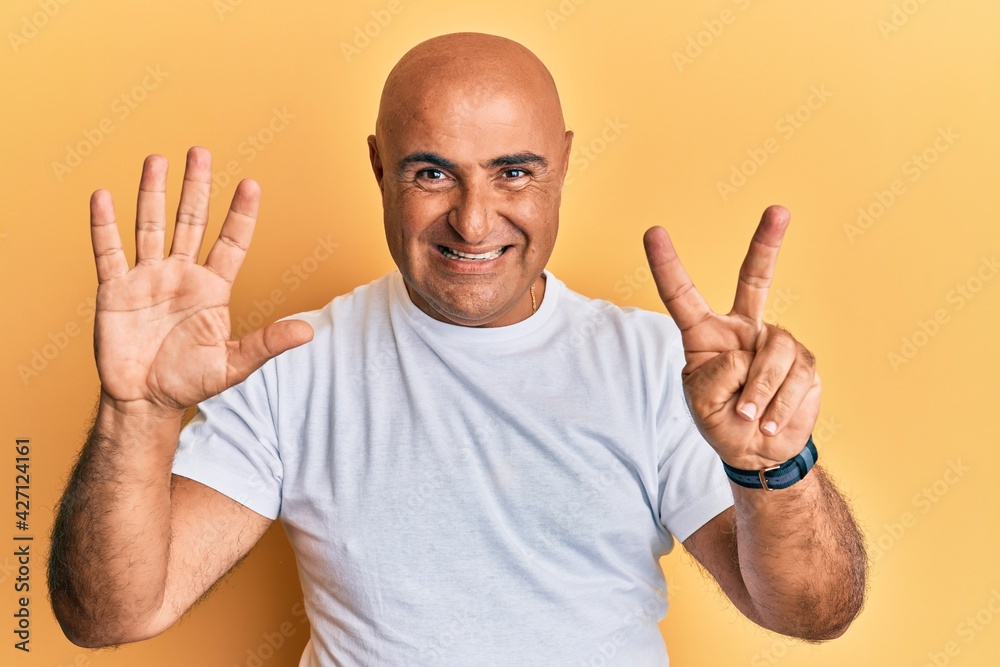 Mature middle east man wearing casual white tshirt showing and pointing up with fingers number seven while smiling confident and happy. Mature middle east man wearing casual white tshirt showing and pointing up with fingers number seven while smiling confident and happy.