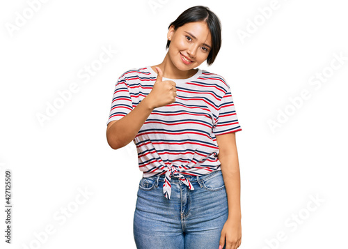Beautiful young woman with short hair wearing casual clothes doing happy thumbs up gesture with hand. approving expression looking at the camera showing success.