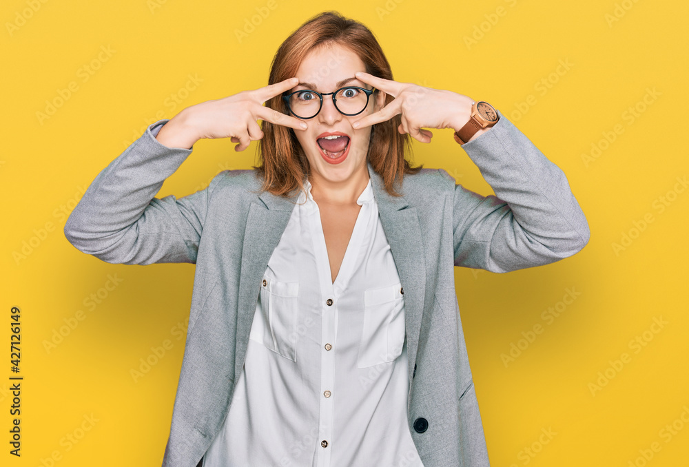 Young caucasian woman wearing business style and glasses doing peace symbol with fingers over face, smiling cheerful showing victory Young caucasian woman wearing business style and glasses doing peace symbol with fingers over face, smiling cheerful showing victory