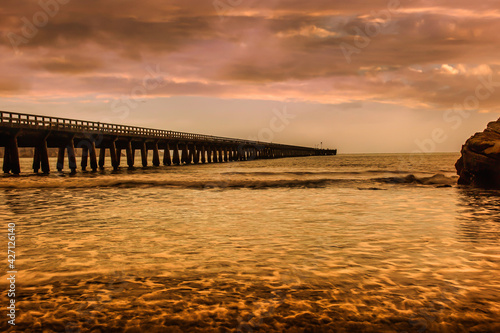 Red cloudscape reflected on the sea at Tolaga Bay beside the historic landmark pier.