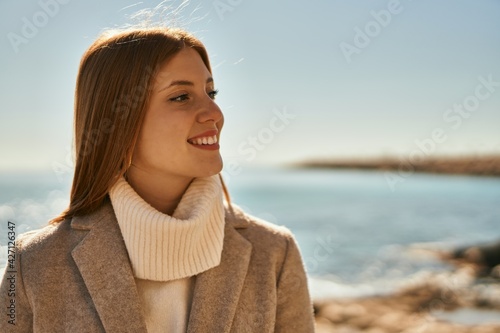 Young redhead girl smiling happy standing at the beach.