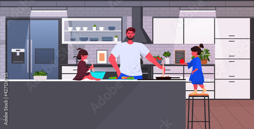 young father with little daughters cooking food fatherhood parenting concept home kitchen interior