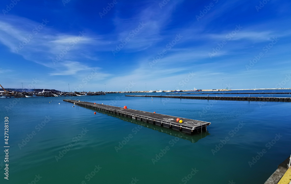 Pontili di legno sul mare con boe e vista sul porto  in una giornata di sole