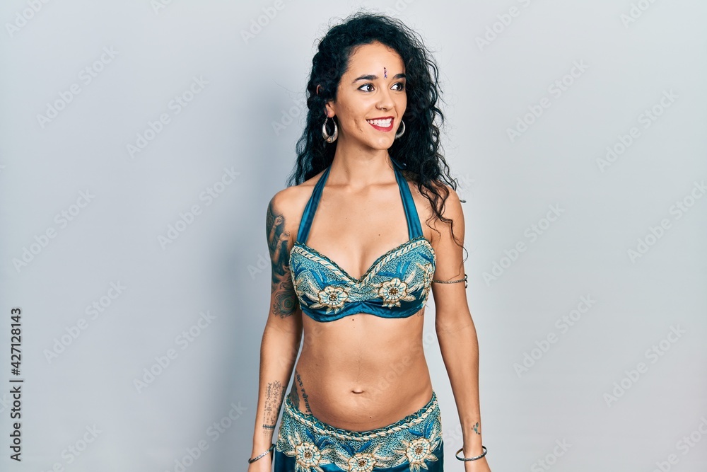 Young woman wearing bindi and traditional belly dance clothes looking away to side with smile on face, natural expression. laughing confident. Young woman wearing bindi and traditional belly dance clothes looking away to side with smile on face, natural expression. laughing confident.