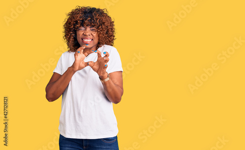 Young african american woman wearing casual white tshirt disgusted expression, displeased and fearful doing disgust face because aversion reaction. with hands raised