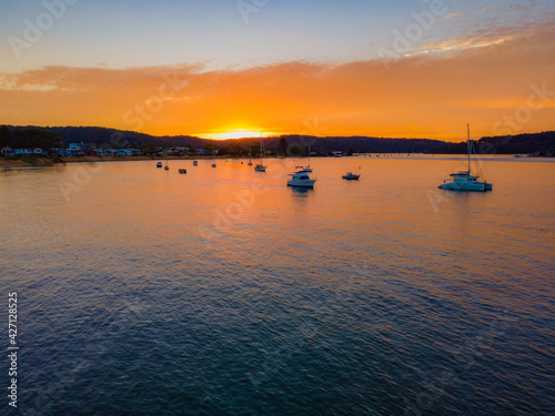 Aerial sunrise waterscape over the channel with orange clouds and boats below © Merrillie