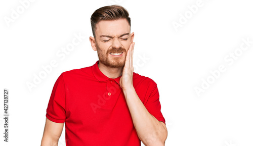 Young redhead man wearing casual clothes touching mouth with hand with painful expression because of toothache or dental illness on teeth. dentist
