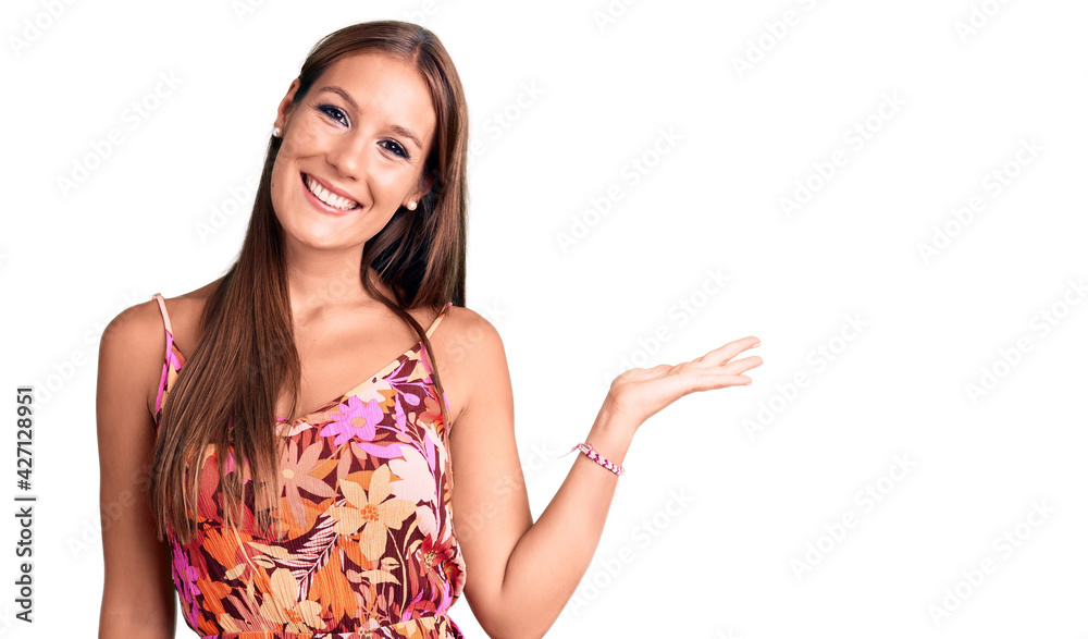 Young beautiful hispanic woman wearing casual clothes smiling cheerful presenting and pointing with palm of hand looking at the camera. Young beautiful hispanic woman wearing casual clothes smiling cheerful presenting and pointing with palm of hand looking at the camera.