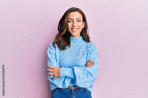 Young brunette woman wearing casual winter sweater over pink background happy face smiling with crossed arms looking at the camera. positive person.