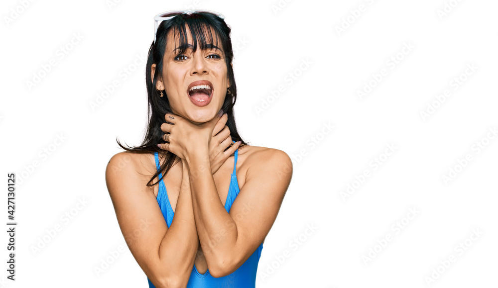 Obraz premium Young hispanic woman wearing swimsuit and sunglasses shouting suffocate because painful strangle. health problem. asphyxiate and suicide concept.