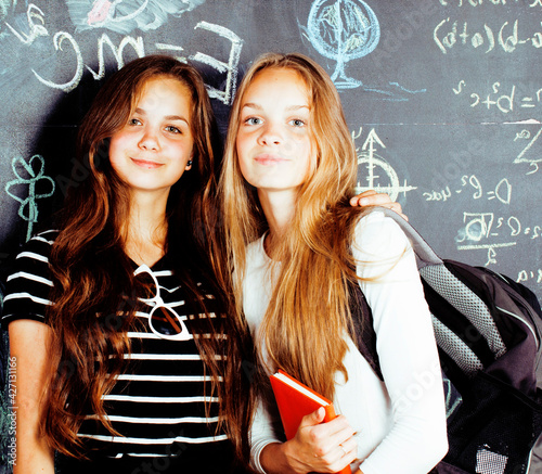 back to school after summer vacations, two teen real girls in classroom with blackboard painted together, lifestyle real people concept