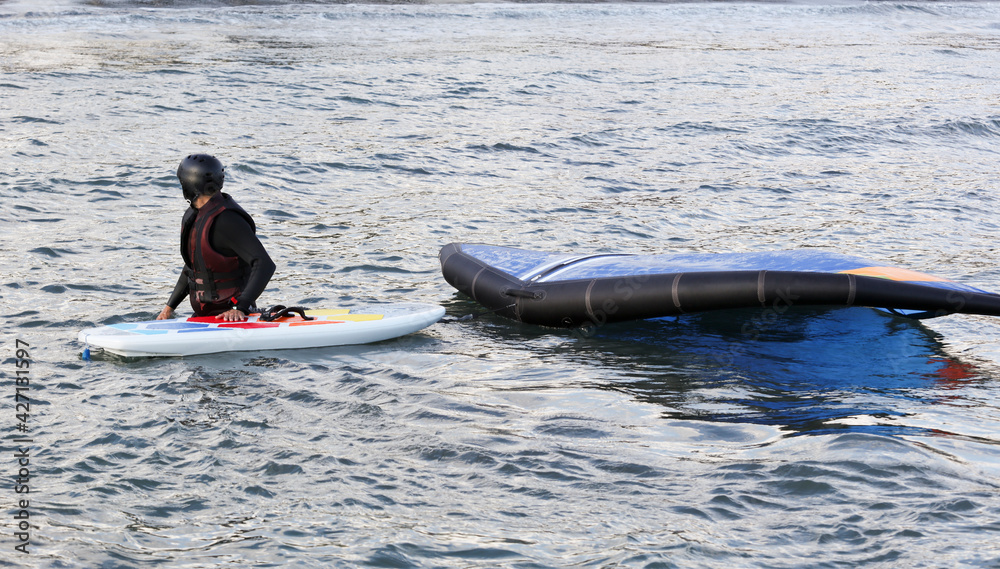 Naklejka premium waterman with complete equipment, paddleboard and hydrofoil in the water