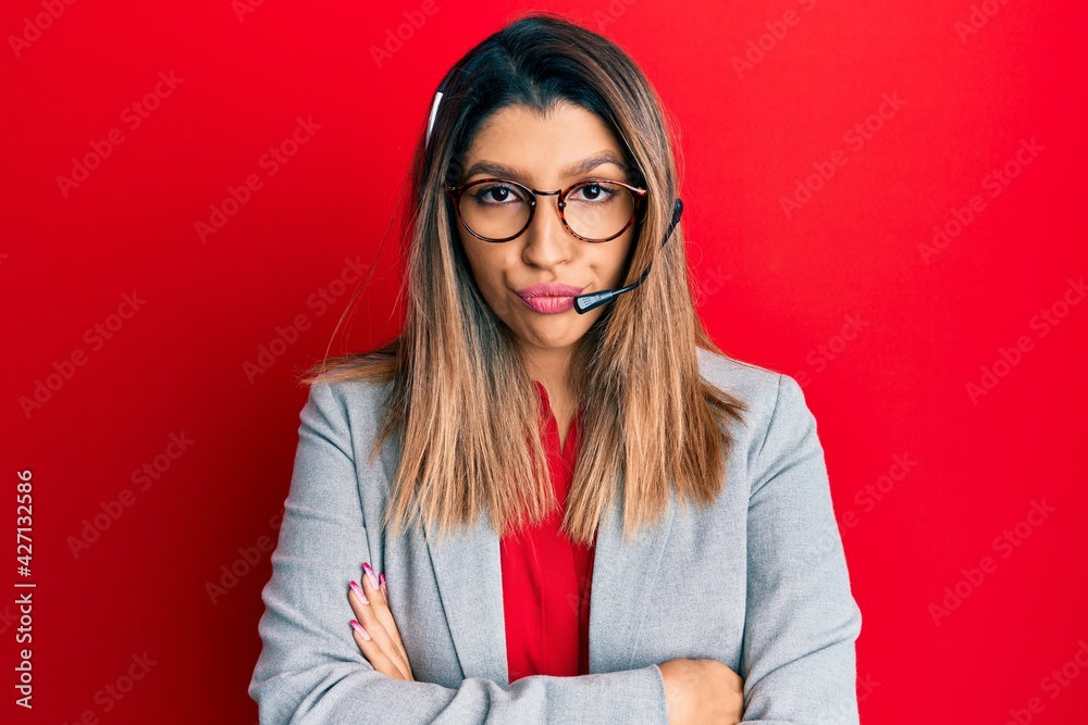 Beautiful brunette woman working at the office wearing operator headset skeptic and nervous, disapproving expression on face with crossed arms. negative person. Beautiful brunette woman working at the office wearing operator headset skeptic and nervous, disapproving expression on face with crossed arms. negative person.