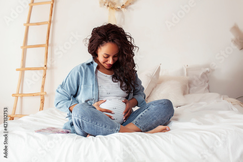 young pretty african american woman pregnant laying in bed, lifestyle people concept