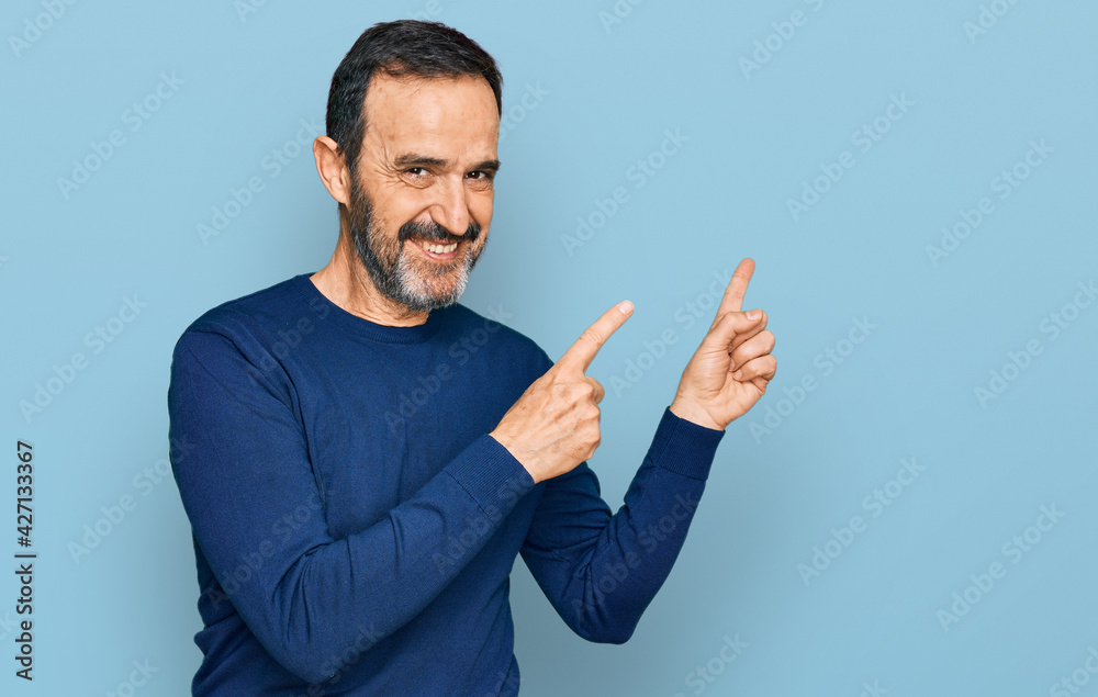 Middle age hispanic man wearing casual clothes smiling and looking at the camera pointing with two hands and fingers to the side. Middle age hispanic man wearing casual clothes smiling and looking at the camera pointing with two hands and fingers to the side.