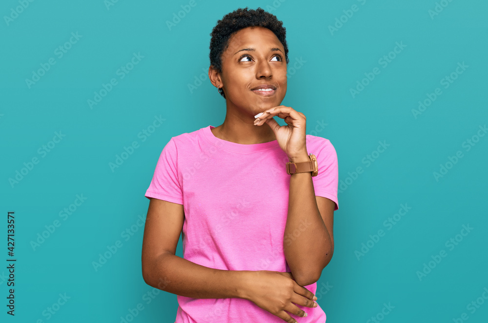 Young african american woman wearing casual clothes with hand on chin thinking about question, pensive expression. smiling and thoughtful face. doubt concept. Young african american woman wearing casual clothes with hand on chin thinking about question, pensive expression. smiling and thoughtful face. doubt concept.