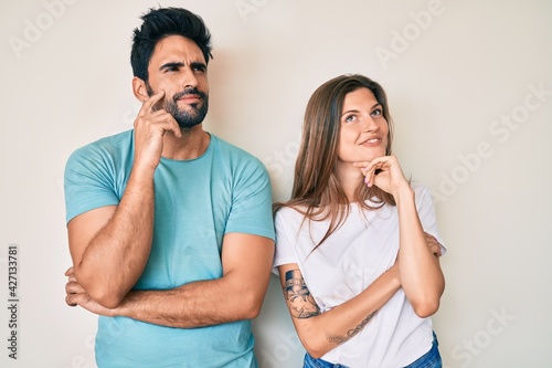 Beautiful young couple of boyfriend and girlfriend together with hand on chin thinking about question, pensive expression. smiling and thoughtful face. doubt concept.