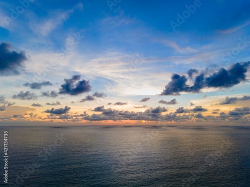 Beautiful sunset over the clam sea with cloud and sky background. Sunset over tropical beach. Nature summer concept. Peak sunset over sea with yellow light reflect in cloud.