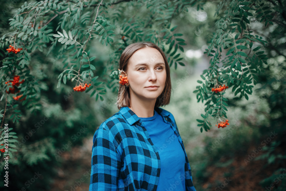 Autumn fall summer woman portrait. Closeup portrait of beautiful Caucasian middle age woman in park. Pensive woman with red rowan tree berries on her ear outdoor. Natural beauty. Autumn fall summer woman portrait. Closeup portrait of beautiful Caucasian middle age woman in park. Pensive woman with red rowan tree berries on her ear outdoor. Natural beauty.