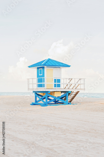 Beautiful light airy tropical Florida landscape with blue yellow lifeguard house. American Florida beach ocean view with lifeguard tower, water, sand and sky. Empty beach at sunset or sunrise outdoor © anoushkatoronto