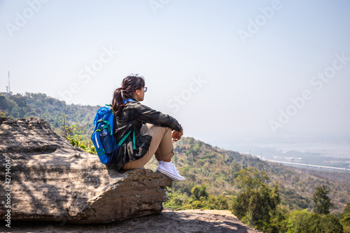 Freedom traveler woman alone sitting on mountain with bag and a beautiful nature