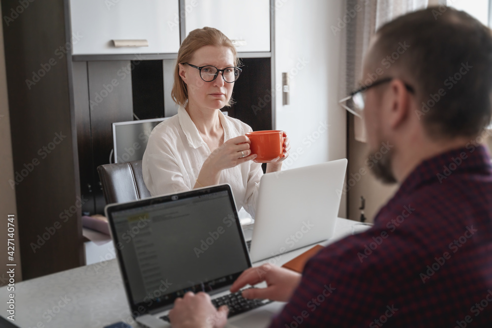 Adult young couple husband and wife remotely working together on laptop at home on self-isolation