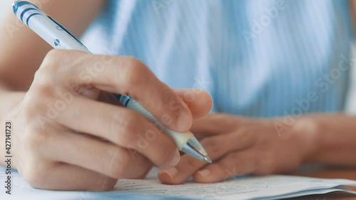 HD Close up hand of business women use pen writing document paper. Female hand close up writing with a blue pen on a white sheet. Woman writes information on a piece of paper.