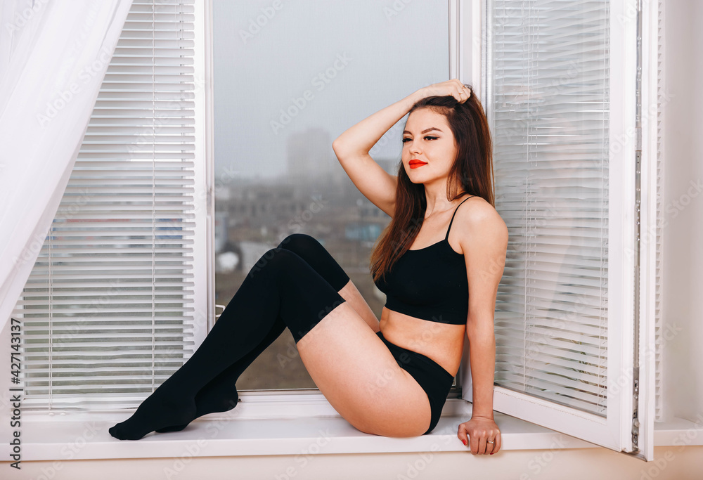 Obraz premium Beautiful sexy young woman in black lingerie. Sexy young brunette woman in black sensual lingerie and in stockings posing. Alluring young woman in sexy lingerie. Beauty fashion. Femininity, sensuality