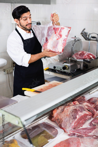 Satisfied man butcher is demonstraiting meat in the market.
