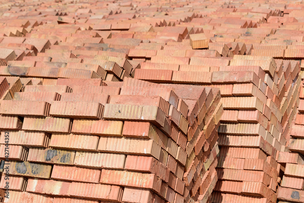 Solid building bricks stacked on a pallet in a pyramid. Many red corrugated bricks. Construction background concept.