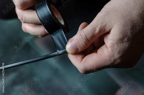 A man is insulating a black electrical wire.