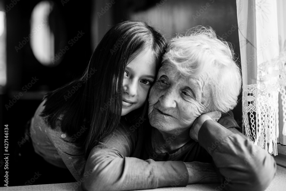 Little girl hugs her old grandmother. Black and white photo.