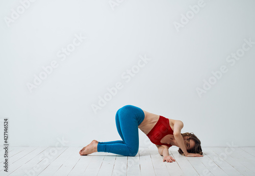 A woman is kneeling on the floor with her arm bent and yoga asana exercises