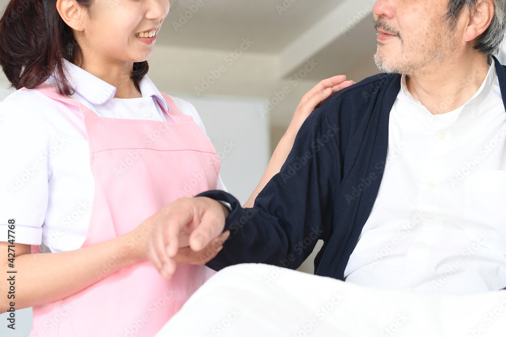 ベッドで寝たきりのお年寄りと介護士の女性
ベッドで寝たきりのお年寄りと介護士の女性